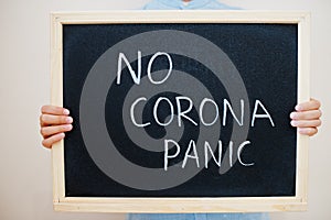 No corona panic. Coronavirus concept. Boy hold inscription on the board