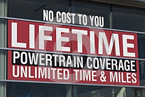 NO COST TO YOU LIFETIME POWERTRAIN COVERAGE UNLIMITED TIME AND MILE sign at a car dealership