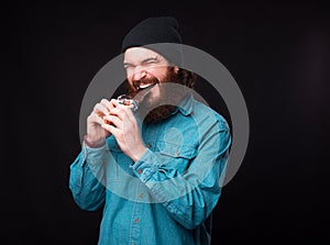 No diet. Bearded hipster man in blue shirt eating dark chocolate over