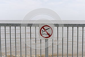 No diving sign on a fence beside a body of water