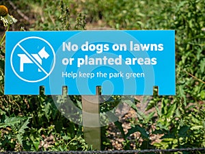 A no dogs on lawns or planted areas, help keep the park green sign