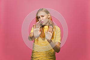 No, enough. Displeased young girl show stop gesture, demanding to cease on pink background. Quarrel, dispute, conflict