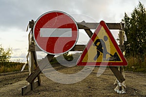 No entry road sign and roadworks sign on dirt road