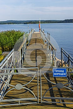 No entry sign on closed gate of wooden pier on summer lake