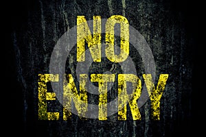 â€œNo Entryâ€ warning sign in yellow letters painted over dark grungy grey concrete wall