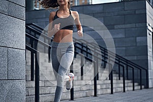 No face shot of young athletic lady running at the city stadium with urban stairs background