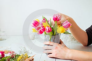 No face young man making spring bouquet using tulips. Online self-education of floristry. Learning flower arranging