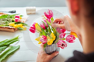 No face young man making spring bouquet using tulips. Online self-education of floristry. Learning flower arranging. Flowers