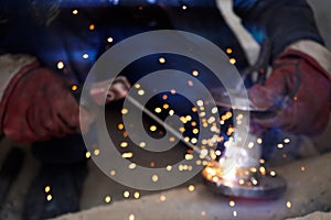 No focus.Close-up welder working with electrode at semi-automatic arc welding in manufacture production plant.Bright sparks from