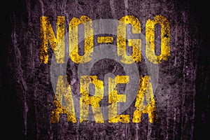 â€œNo-Go Areaâ€ danger warning sign in yellow letters painted over dark grungy concrete wall texture background