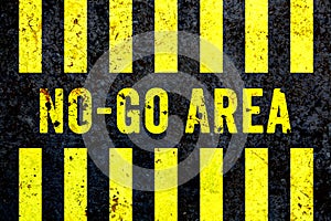 â€œNo-Go Areaâ€ warning sign in yellow letters painted on grungy concrete wall with yellow stripes.