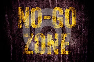 â€œNo-Go Zoneâ€ warning sign in yellow letters painted over dark grungy concrete wall texture background.