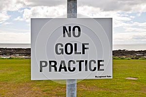 No golf practice sign with clouds, grass and sky