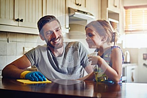 No hassles with housework thanks to Dads little helper. a father and his little daughter cleaning a kitchen surface photo