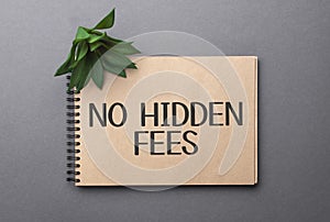 No Hidden Fees text on craft colored notepad and green plant on the dark background