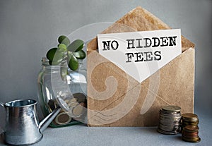 NO HIDDEN FEES text is written on white paper on an antique envelope, which lies on the table along with a stack of coins, a glass