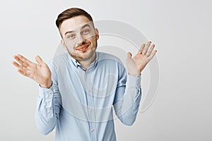 No idea guess yourself. Portrait of happy carefree and careless good-looking male coworker in blue shirt shrugging with