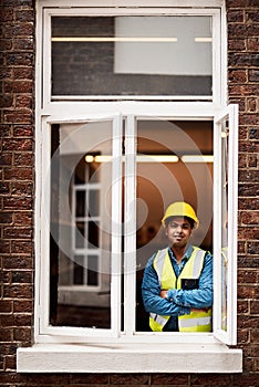 No job too big. No job too small. a young engineer standing in the window of a construction site.