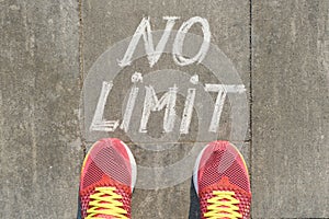 No limit text on gray sidewalk with woman legs in sneakers, top view