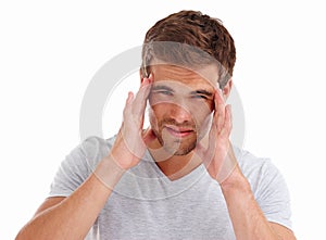 No loud music for me. a young man holding his head in pain while standing in a studio- isolated on white.