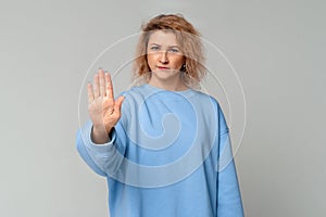 No means no. Portrait of serious middle age woman showing stop gesture standing with stretched hand, standing in trendy blue