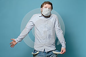 No money. Man in a medical mask with empty pockets and a questioning look. Concept of unemployment and crisis due to the