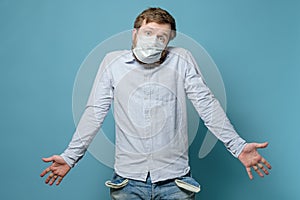 No money. Perplexity man in a medical mask with empty pockets and a questioning look. Concept of economic crisis due to