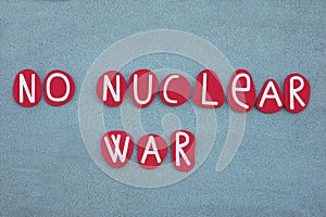 No nuclear war, pacifist slogan composed with red colored stone letters over green sand photo