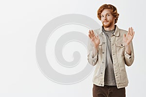 No offence sorry pal. Portrait of intense redhead male with beard feeling awkward smiling tight from discomfort raising