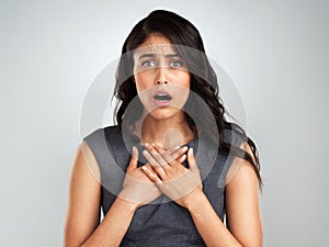 No one likes to hear bad news. a young woman looking surprised while posing against a white background.