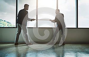 No one pushes you to achieve more than your competitor. two young businessmen pulling on a rope in a game of tug of war.