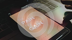 No pain no gain inscription on smartphone screen. Rays of light come from screen. Male hand flapping with fingers