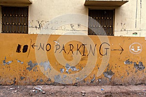 `No Parking` graffiti on yellow wall