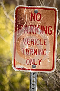 No parking sign that has been weathered from the outdoors