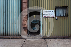 No parking sign on side of industrial building with tin walls