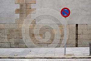 No parking sign, sidewalk and grey wall