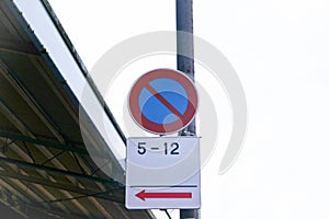 No parking sign traffic circle sign blue red attached to steel pole on side of road on white sky is background