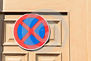 No parking sign on the wooden door to protect entrance from the car drivers .