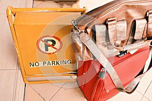 No parking sign on the yellow board with travel bags put beside it on the road in front of the airport.