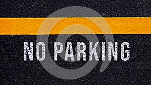 No Parking written and yellow line on the road in middle of the asphalt road, No Parking word on street