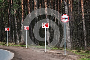 No passing road sign and arrows on winding road in the forest