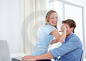 No peeking. A young woman covering her boyfriends eyes as he works on a laptop.