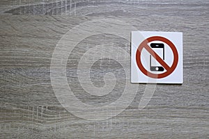 No phone allowed sign on the wooden wall with space for adding text on the left