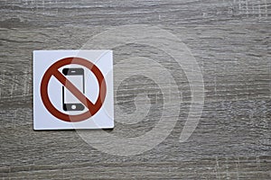 No phone allowed sign on the wooden wall with space for adding text on the right