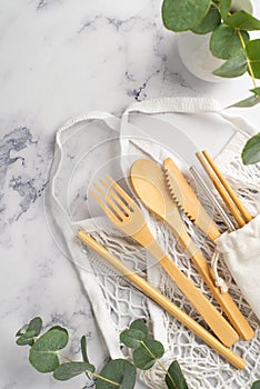 No plastic concept. Top view vertical photo of wooden cutlery fork spoon knife chopsticks white string bag steel straw cleaning