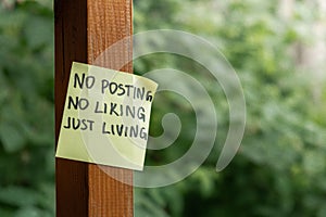 NO POSTING NO LIKING JUST LIVING text on paper note on background of greenery garden. Concept of social media technology