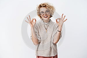 No problem relax, deal. Portrait of chill and carefree charming pleasant blond woman in glasses and sweater showing okay