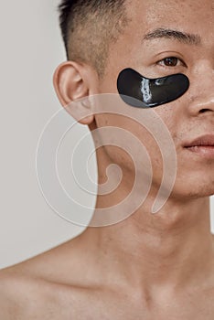 No puffiness. Close up portrait of shirtless young asian man with black patches under the eyes looking away isolated photo