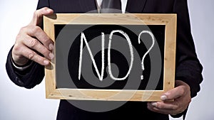 No with question mark written on blackboard, businessman holding sign, concept