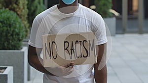 NO RACISM on cardboard poster in hands of African American male protester activist. Stop Racism concept, No Racism